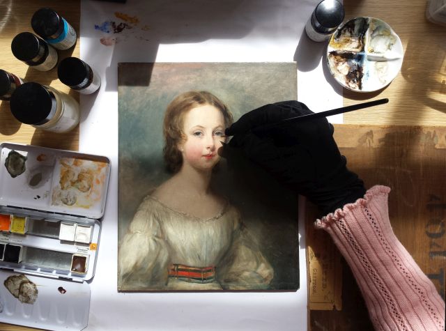 Conservator examining a painting in the historic rooms at Woburn Abbey