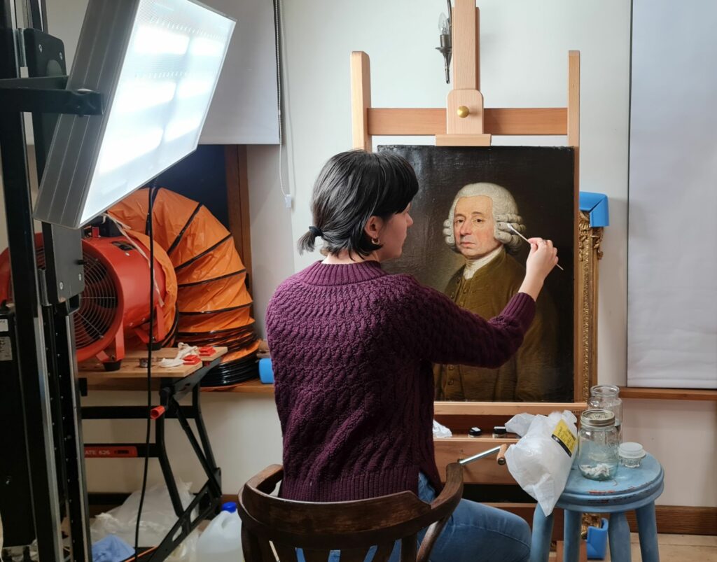 Valeriia Kravchenko cleaning a portrait from the Huguenot Museum